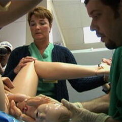 Image shows a lifelike pregnant robot woman in labor during a medical training class.