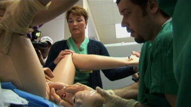 Image shows a lifelike pregnant robot woman in labor during a medical training class.